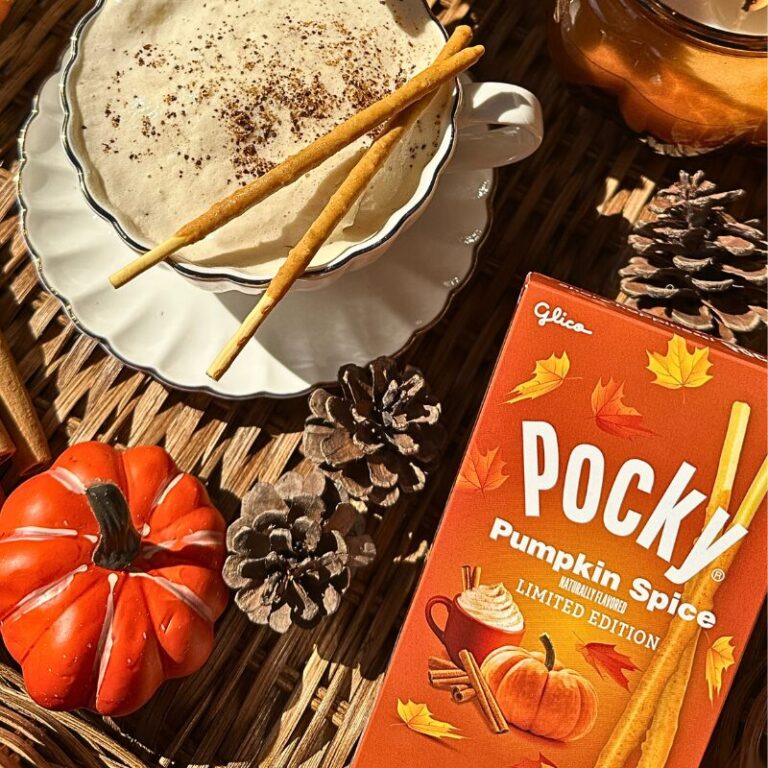 A box of Pocky Pumpkin Spice next to a cup of cappuccino with Pocky Pumpkin Spice sticks on top.